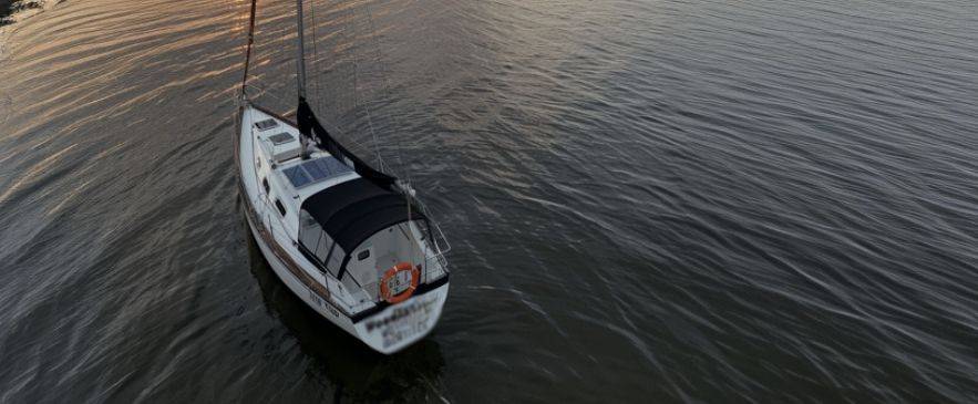 A sailboat anchored at sunset, prepared for bareboat cruising