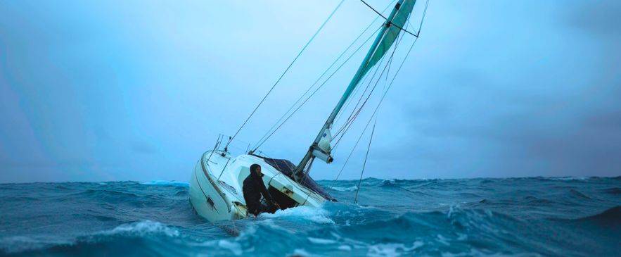 safety drills for sailors, Sailboat heeling in rough sea during sailing storm safety drill with sailor managing the helm