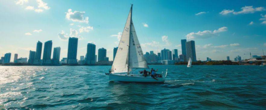 Sailboat with ASA 102 students practicing sail trim in Biscayne Bay near downtown Miami skyline