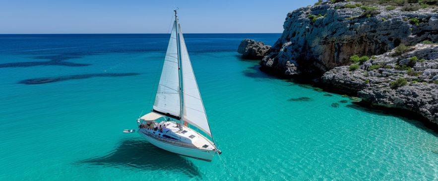 Sailing Internationally Sailboat anchored in shallow turquoise bay by rocky coastline – North America résumé freedom