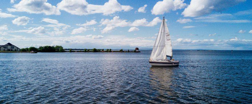 Sailing Internationally Single-masted sailboat on open tidal waters under cloudy sky – no universal sailing license