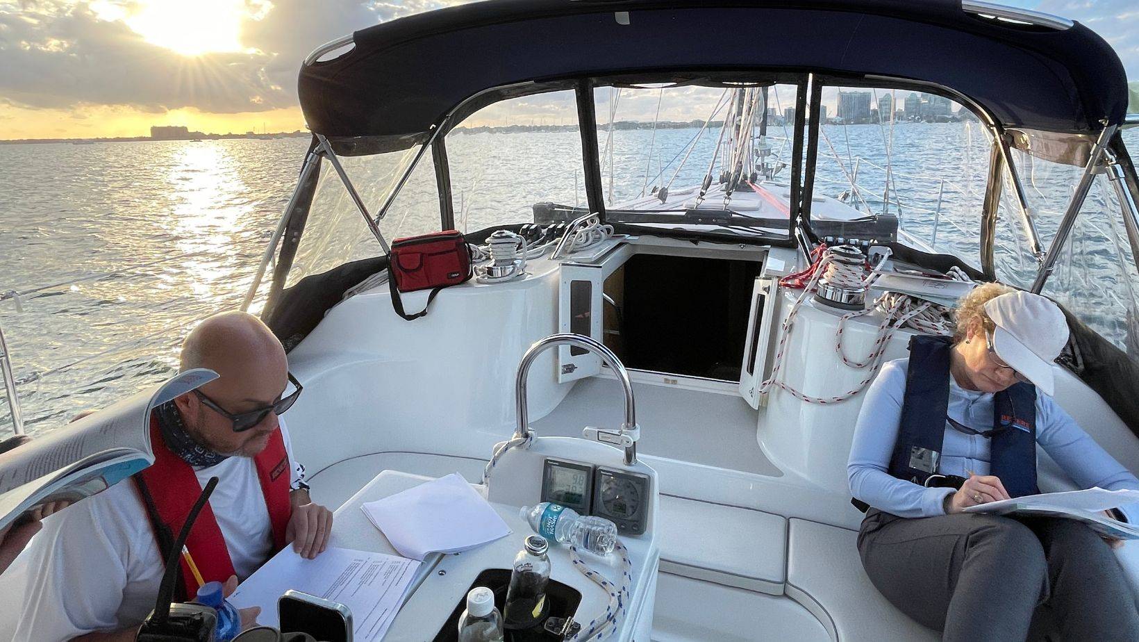 Sailing navigation basics lesson with students practicing chart reading on a sailboat in Biscayne Bay